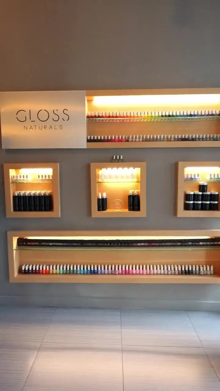 The Gloss Naturals polish wall inside Gloss Nail Bar, with lit shelves of lacquer in a range of colors