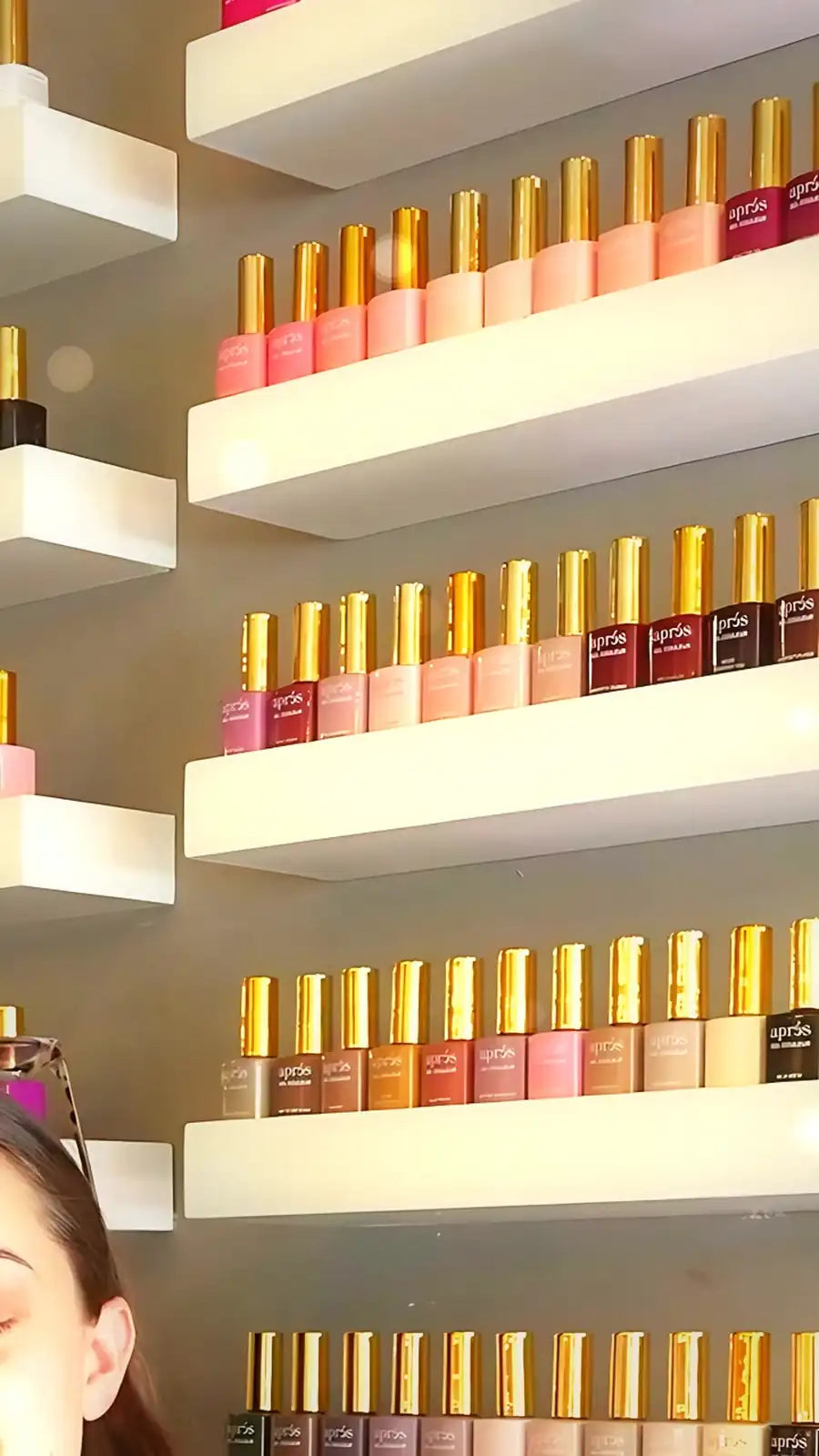 Rows of gel polish bottles in many shades on white wall shelves